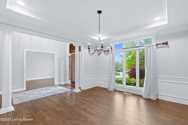 unfurnished dining area with an inviting chandelier, ornamental molding, decorative columns, and a decorative wall