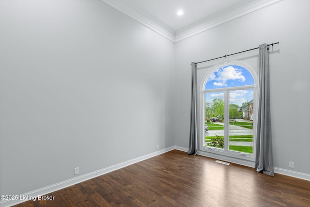 empty room featuring crown molding, a high ceiling, baseboards, dark wood-type flooring, and visible vents