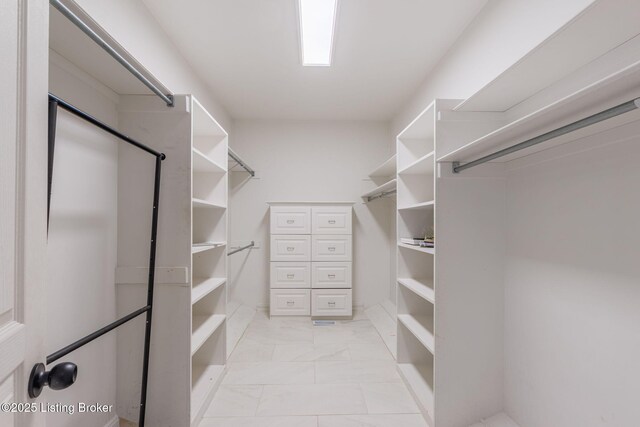 walk in closet featuring marble finish floor