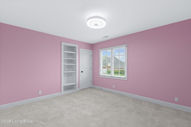 unfurnished room featuring carpet floors, built in features, and baseboards