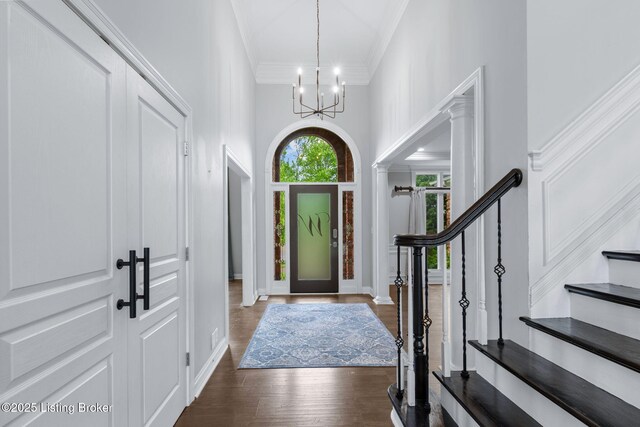 entrance foyer featuring an inviting chandelier, stairs, crown molding, and wood finished floors
