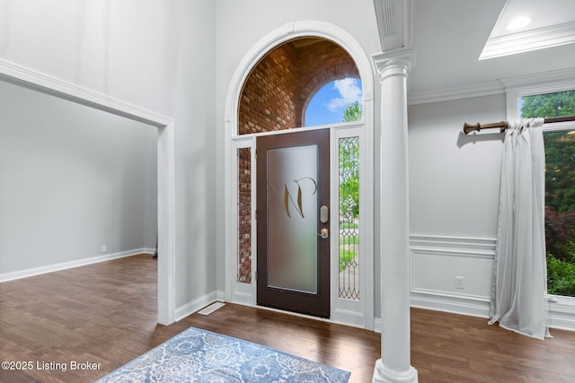 entrance foyer featuring baseboards, ornamental molding, ornate columns, and wood finished floors