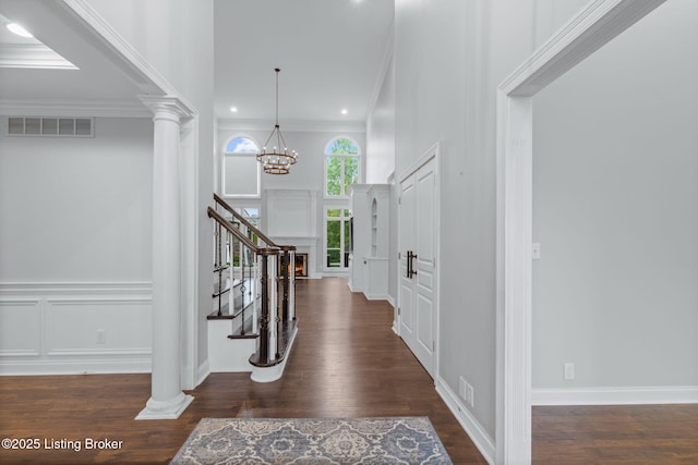 foyer entrance with crown molding, a decorative wall, stairs, and visible vents