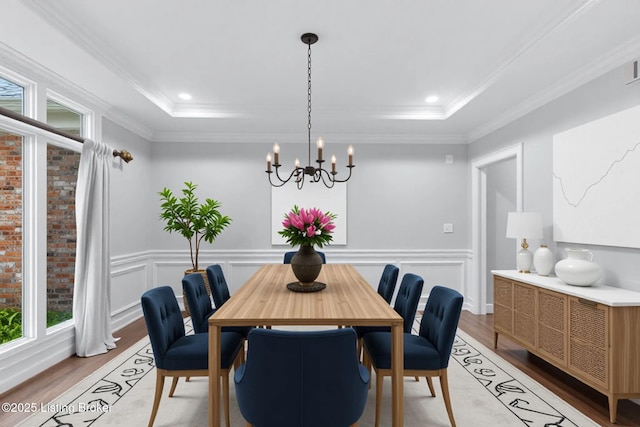 dining room featuring a wainscoted wall, ornamental molding, light wood finished floors, and a chandelier