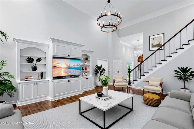 living area featuring a high ceiling, a chandelier, dark wood finished floors, baseboards, and stairway