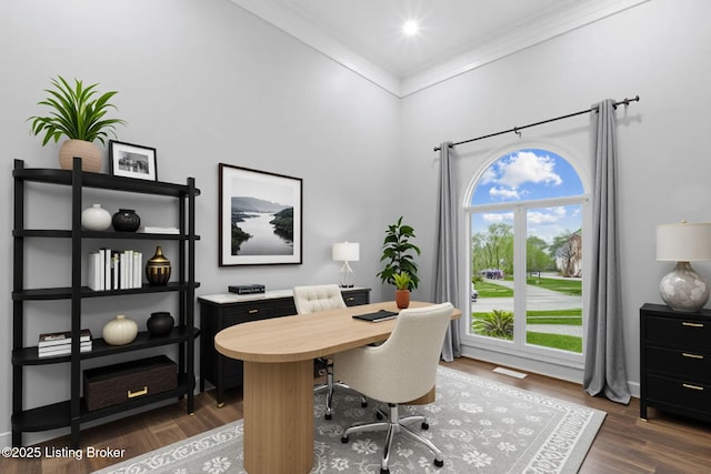 home office with dark wood-type flooring, ornamental molding, baseboards, and a high ceiling