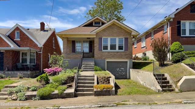 bungalow featuring brick siding, an attached garage, and stairs