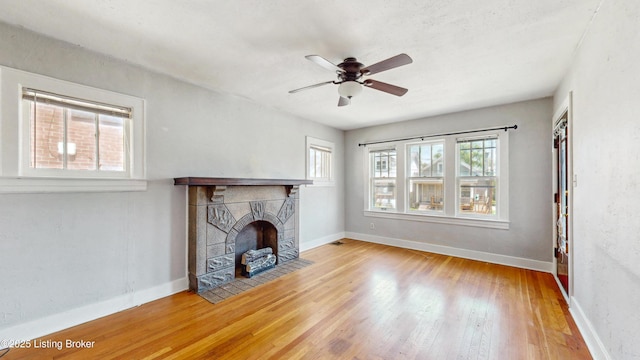 unfurnished living room featuring baseboards, ceiling fan, a wealth of natural light, and wood finished floors