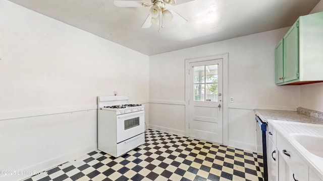 kitchen with gas range gas stove, light floors, light countertops, green cabinetry, and a ceiling fan