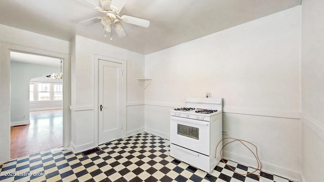kitchen featuring open shelves, baseboards, white gas range, tile patterned floors, and ceiling fan with notable chandelier