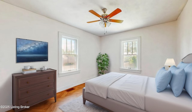 bedroom with a ceiling fan, baseboards, visible vents, and multiple windows