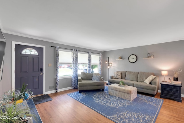 living area with baseboards, wood finished floors, and ornamental molding