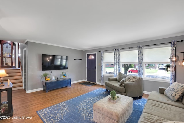 living area with baseboards, wood finished floors, stairs, and ornamental molding