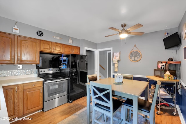 kitchen featuring stainless steel electric range oven, light countertops, brown cabinets, light wood-type flooring, and a ceiling fan
