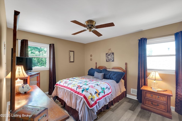 bedroom featuring a ceiling fan, visible vents, wood finished floors, and baseboards