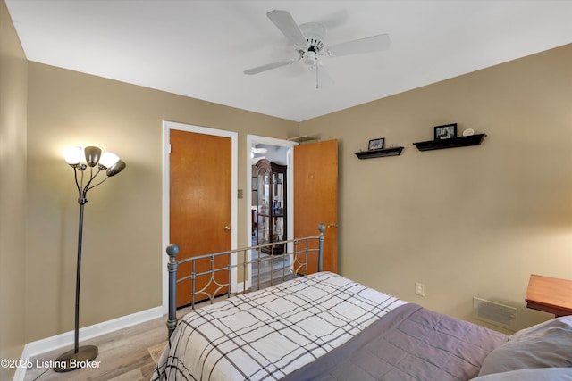 bedroom featuring visible vents, light wood-style floors, a ceiling fan, and baseboards
