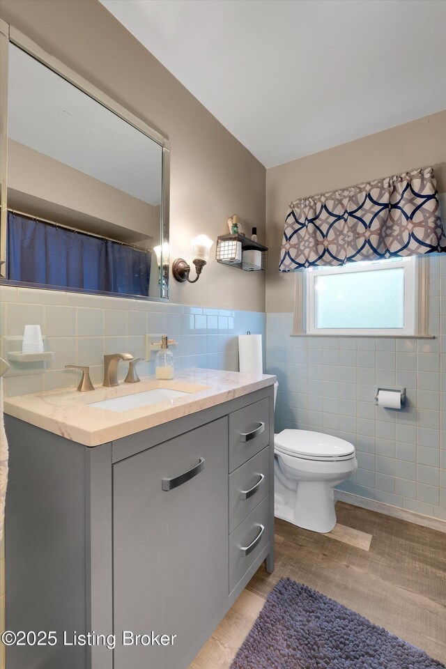 full bathroom with vanity, toilet, wainscoting, and tile walls