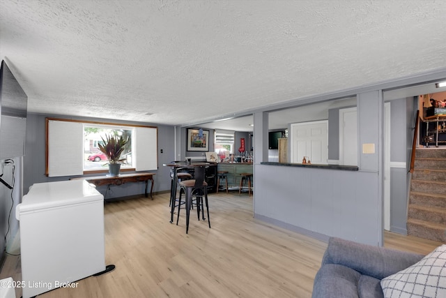 living room with a textured ceiling, a healthy amount of sunlight, light wood-type flooring, and stairway