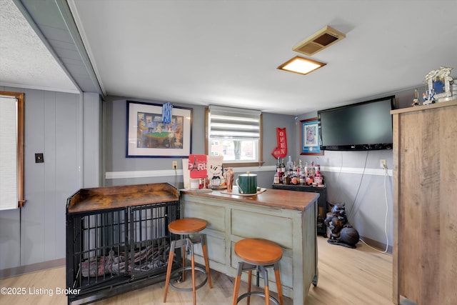 bar with visible vents, wood finished floors, and a bar