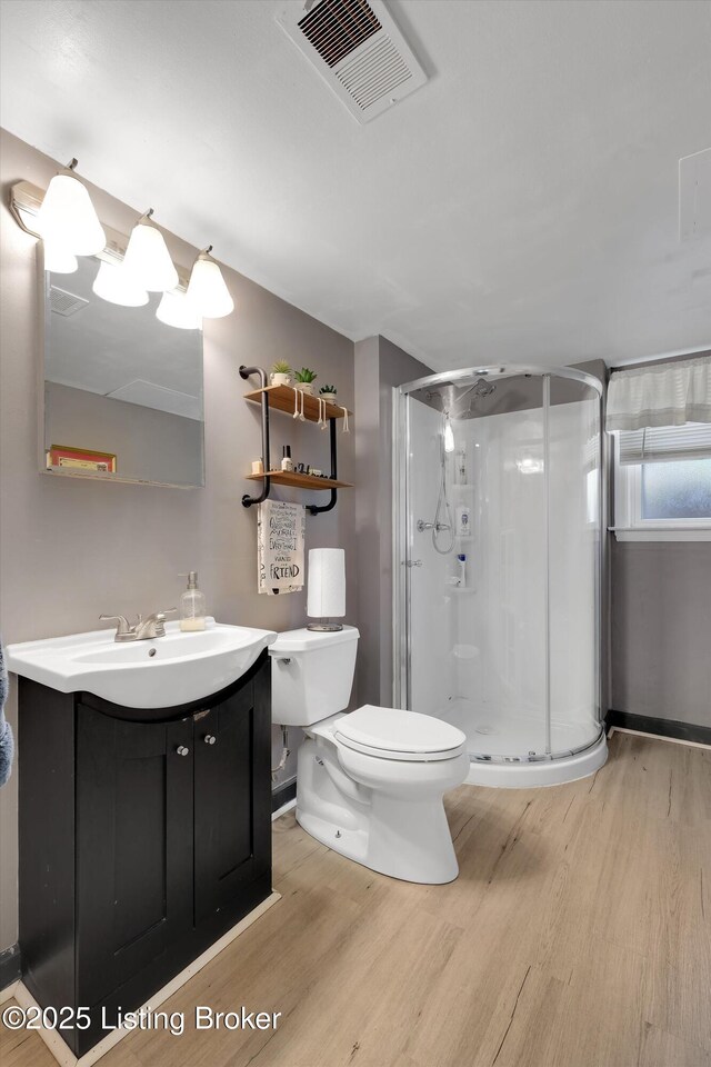 full bathroom with wood finished floors, a shower stall, toilet, vanity, and visible vents