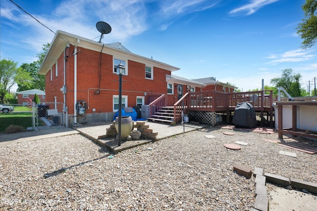 rear view of property with a deck, fence, and a gate