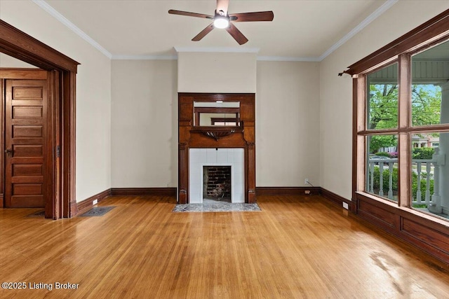 unfurnished living room featuring a tiled fireplace, light wood-type flooring, ornamental molding, and a ceiling fan