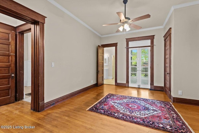 empty room with crown molding, a ceiling fan, wood finished floors, and french doors