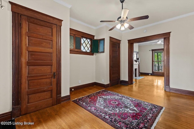 foyer entrance featuring baseboards, wood finished floors, ceiling fan, and crown molding