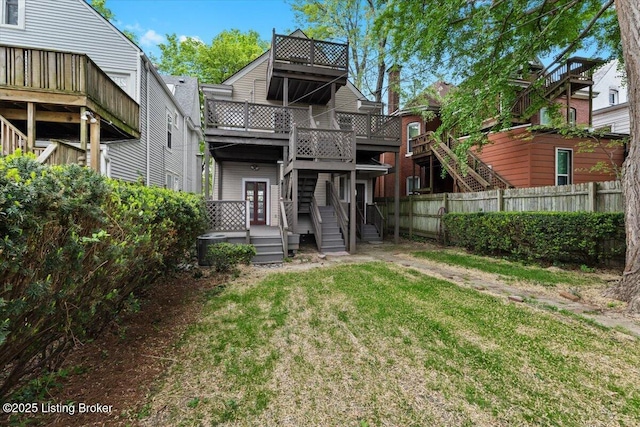 back of property featuring fence, a deck, and a lawn