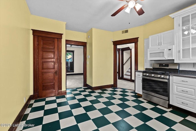kitchen with light floors, white microwave, baseboards, visible vents, and stainless steel range with gas stovetop