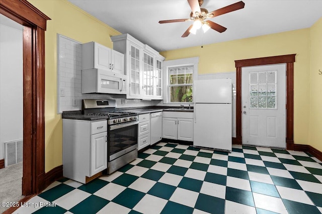 kitchen with white appliances, tile patterned floors, dark countertops, visible vents, and a ceiling fan
