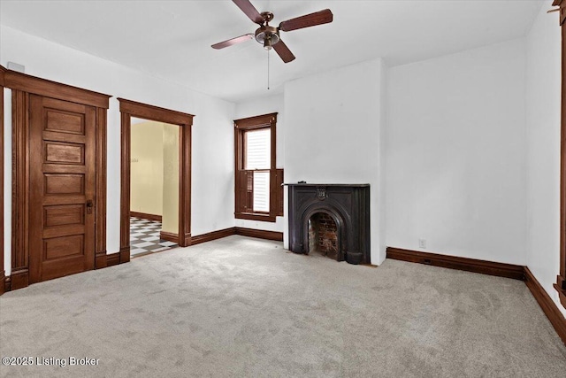 unfurnished living room with a fireplace, baseboards, a ceiling fan, and carpet floors