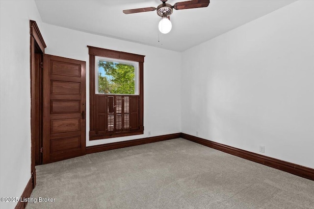 carpeted spare room featuring ceiling fan and baseboards