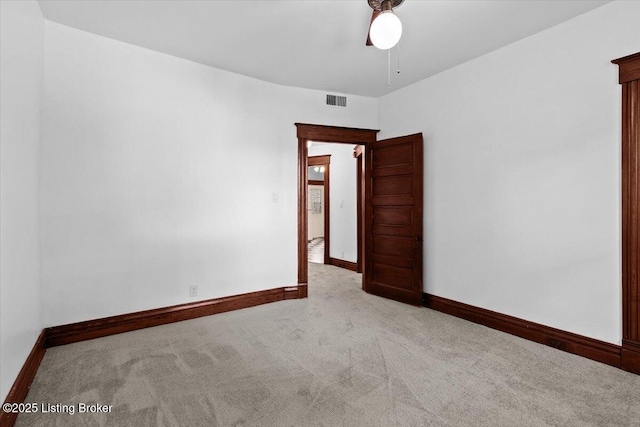 carpeted empty room featuring a ceiling fan, visible vents, and baseboards