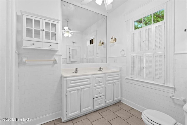 bathroom with double vanity, ceiling fan, toilet, and a sink