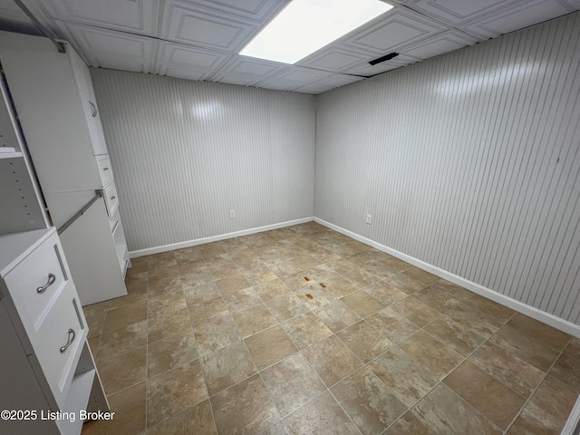 finished basement featuring stone finish flooring, wood walls, and baseboards