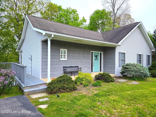 ranch-style house featuring a deck, a shingled roof, and a front yard