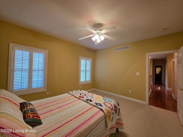 bedroom with carpet flooring, a ceiling fan, visible vents, and baseboards