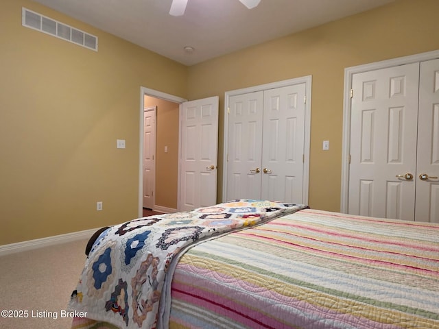 carpeted bedroom featuring a ceiling fan, visible vents, two closets, and baseboards