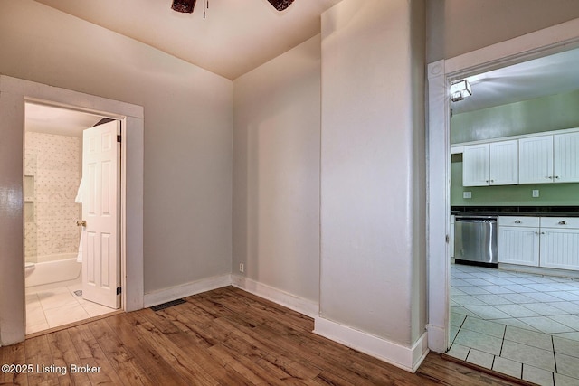empty room featuring baseboards, wood finished floors, and a ceiling fan