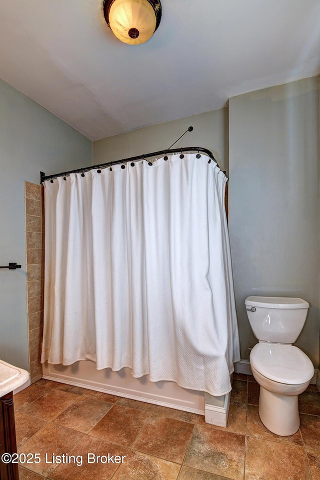 bathroom with shower / tub combo, stone tile flooring, and toilet
