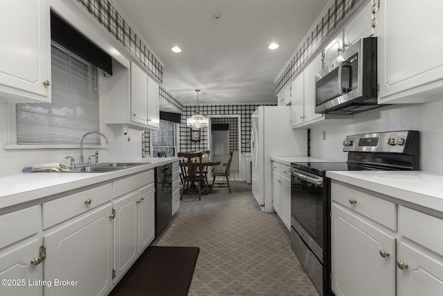 kitchen with white cabinets, a sink, light countertops, stainless steel appliances, and recessed lighting