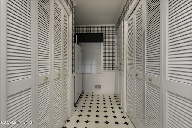 corridor with visible vents, light floors, wainscoting, and wallpapered walls