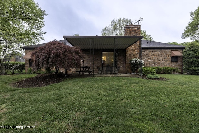 back of house featuring a chimney, a yard, and brick siding