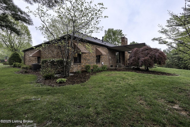 view of property exterior with brick siding, central AC unit, a yard, and a chimney