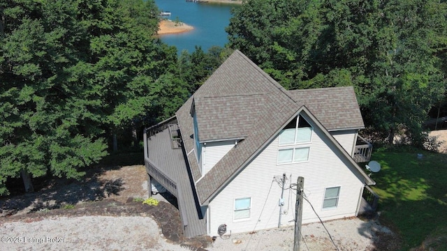 exterior space with a water view and roof with shingles