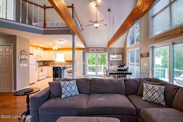living area with light wood-style flooring, ceiling fan, beverage cooler, and high vaulted ceiling