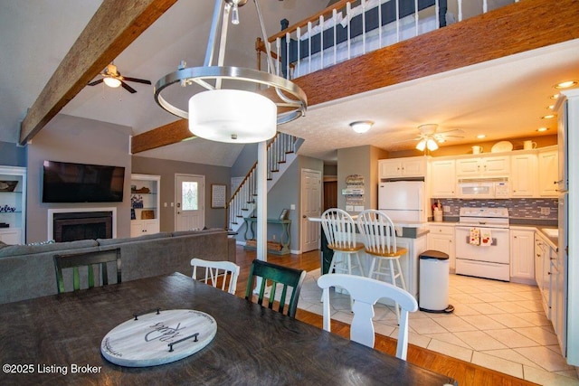 dining area with a fireplace, stairway, ceiling fan, and light tile patterned flooring