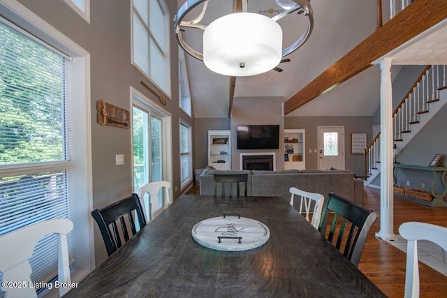 dining room featuring a fireplace, a wealth of natural light, wood finished floors, and a high ceiling