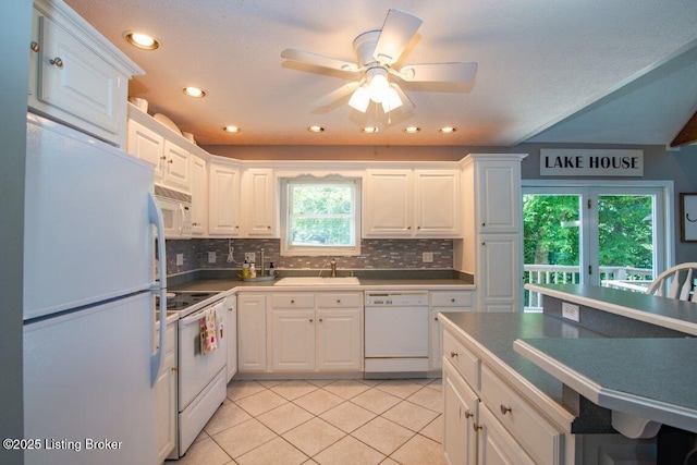 kitchen with a sink, light tile patterned floors, white cabinetry, backsplash, and white appliances